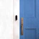 Google Nest Doorbell (Mit Kabel) - smarte Türklingel an der Wand neben blauer Haustür
