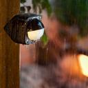Philips Hue Outdoor Sensor links an der Wand im Regen