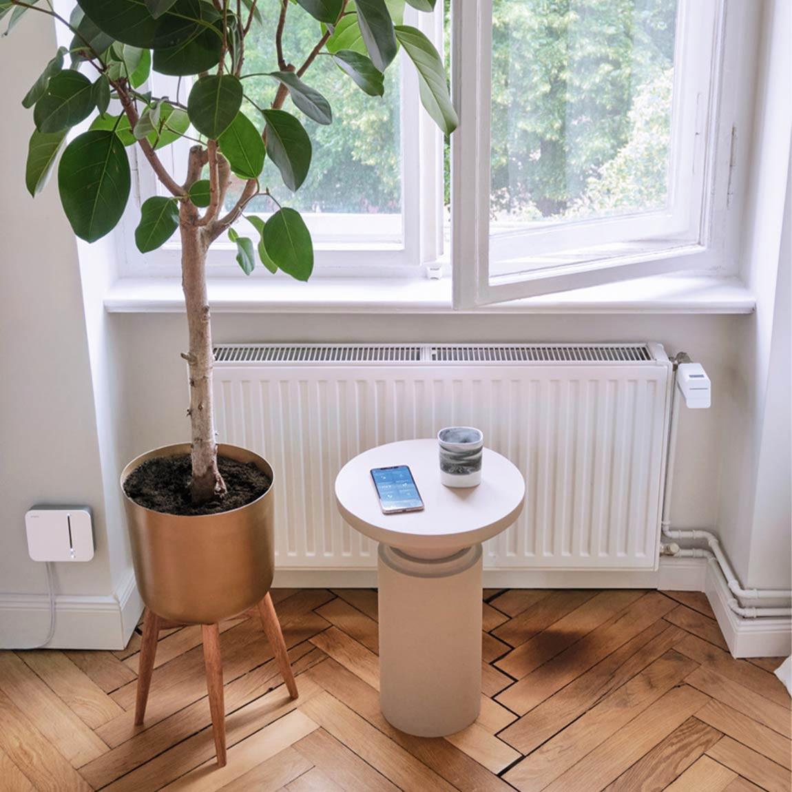 Bosch Smart Home Tür- & Fensterkontakt und Heizkörperthermostat im Wohnzimmer neben iPhone
