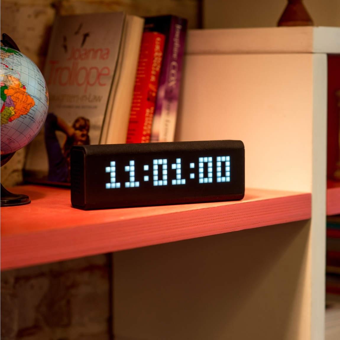 LaMetric Time smarte WLAN-Uhr in schwarz zeigt die Uhrzeit in einem Regal an 